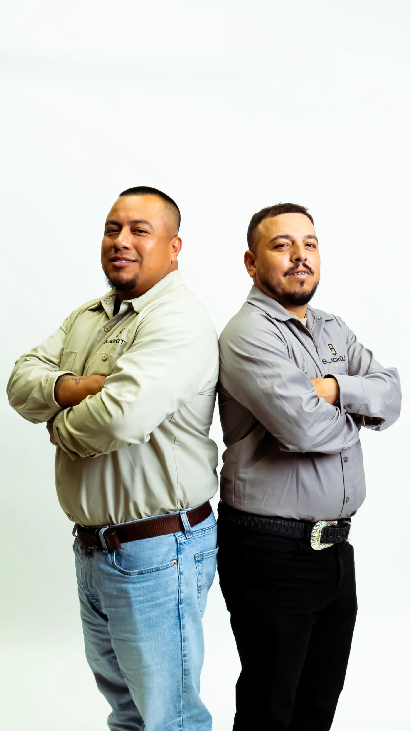 Two Blackout crew leads back to back in work shirts, studio portrait